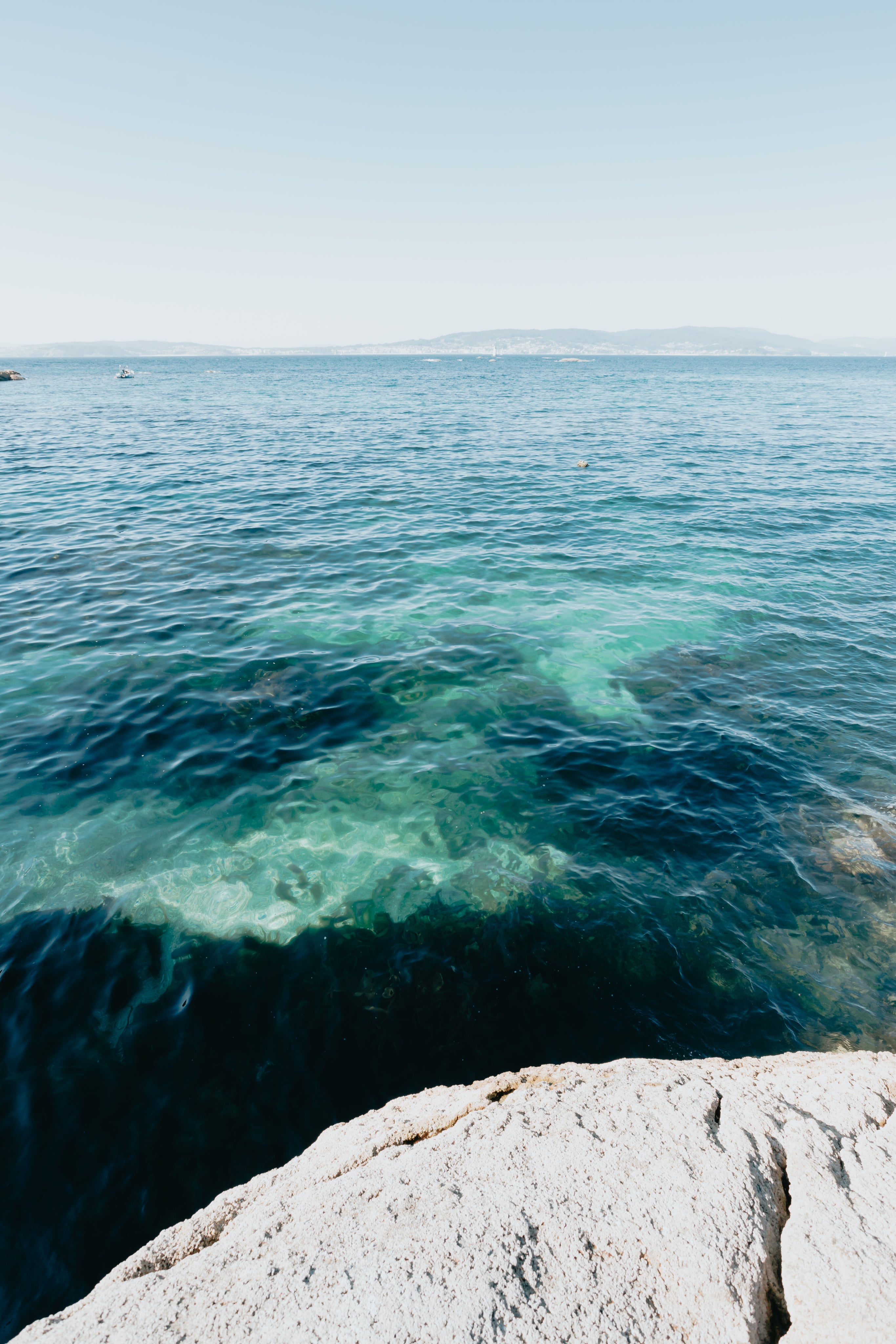 Clear blue sea with a clear blue sky and a blurry mountain 